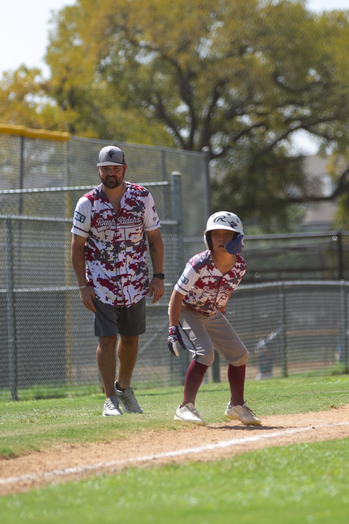 A young baseball player celebrating near a coach after reaching base