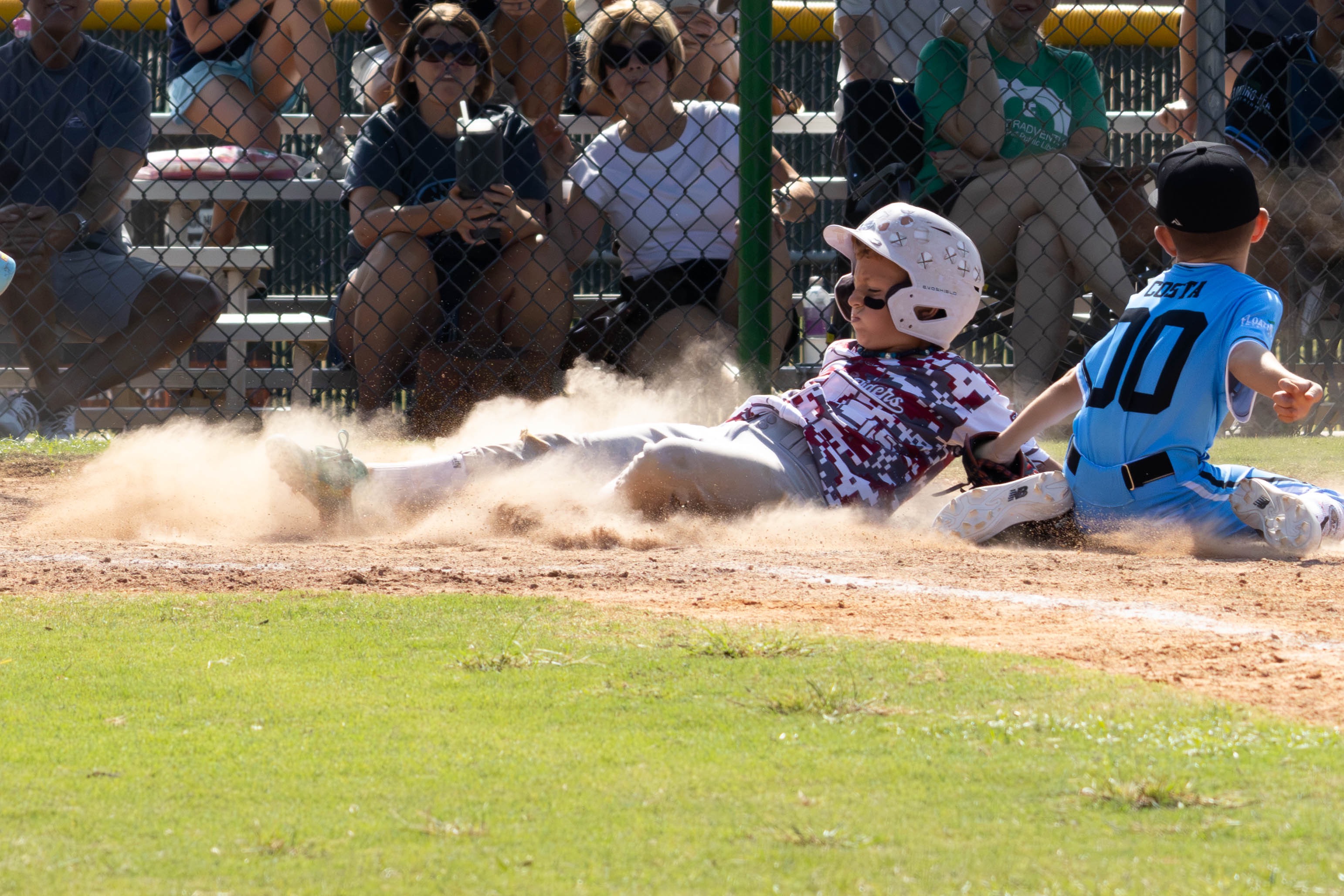 Rough Riders baseball player sliding through the dust during a close play at home