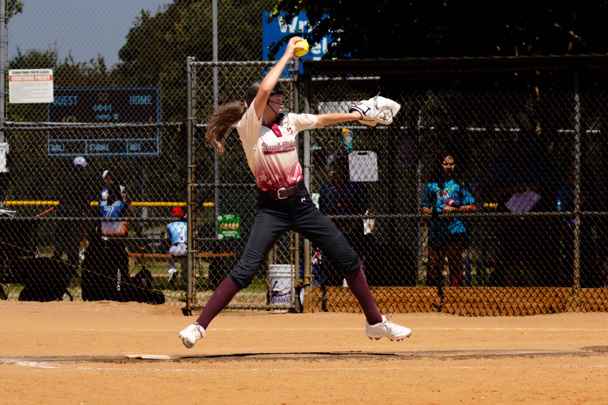 Rough Rider Youth softball pitcher in midair during her delivery